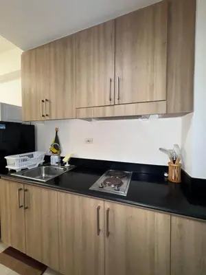 a kitchen with wooden cabinets and a sink at The Chill Lane- Shore Residences in Manila