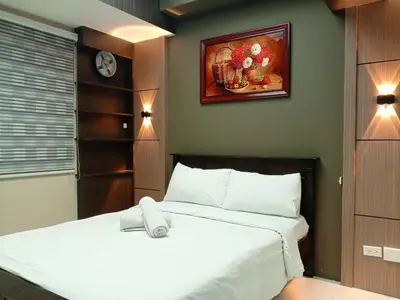 a bedroom with a white bed and a painting on the wall at Cozy Manila Condo Retreat with Shared Pool in Manila