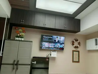 a kitchen with a tv on the wall and a refrigerator at Cozy Manila Condo Retreat with Shared Pool in Manila