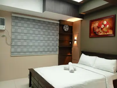 a bedroom with a bed with a clock on the wall at Cozy Manila Condo Retreat with Shared Pool in Manila