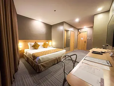 a hotel room with a bed and a desk at Madison 101 Hotel + Tower in Manila