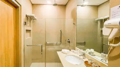 a bathroom with a glass shower and a sink at Madison 101 Hotel + Tower in Manila