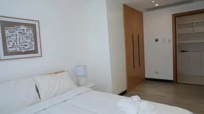 a bedroom with a white bed and a wooden door at Coastal Luxury Residences in Manila
