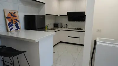 a kitchen with white cabinets and a black refrigerator at Coastal Luxury Residences in Manila