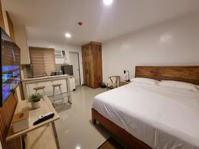 a bedroom with a large bed and a kitchen at Flat 35, Unit E in Manila