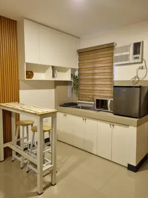 a kitchen with white cabinets and a table with stools at Flat 35, Unit E in Manila
