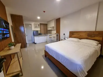 a bedroom with a large bed and a kitchen at Flat 35, Unit E in Manila