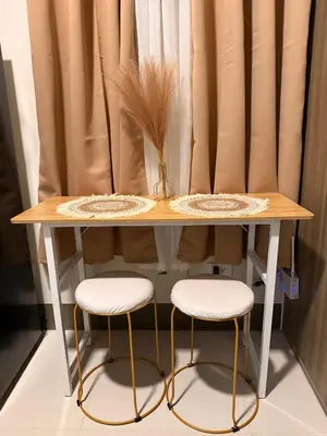 a table with two stools and a vase on it at Cami Haus at Fame Residences in Manila