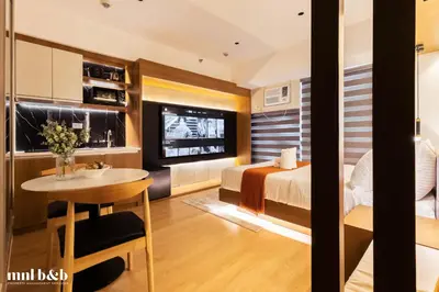 a hotel room with a bed and a table and a tv at Near Venice Mall! Hotel 1BR Unit in Viceroy Residences in Manila