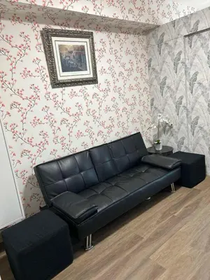 a black leather couch in a room with wallpaper at Family Condo SMB in Manila