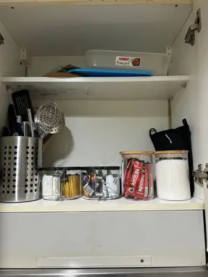 a kitchen shelf with utensils and other kitchen items at Family Condo SMB in Manila