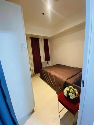 a bedroom with a bed and a table with flowers on it at Azure Urban Condomiun Near Airport in Manila