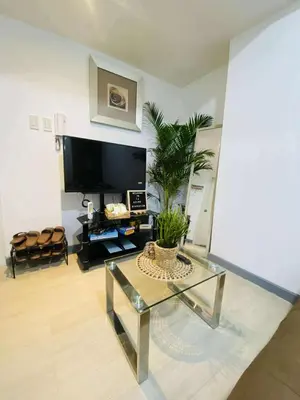 a living room with a glass table and a tv at Azure Urban Condomiun Near Airport in Manila