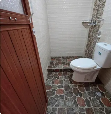 a bathroom with a toilet and a stone floor at Greenhills Garden Square Residences 2BR & 2 Toilets Quezon City in Manila