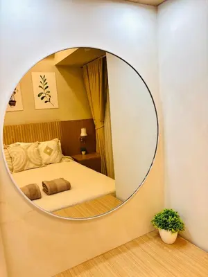 a round mirror in a bedroom with a bed at Luxurious Room in Bel Air Makati - Air Residences in Manila