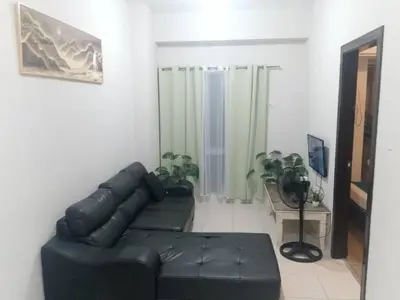 a living room with a black leather couch and a table at Staycation in Brgy Cupang in Manila