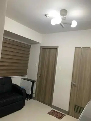 a living room with a black couch and a ceiling fan at Marhulz Two Bedroom Staycation at S Residences in Manila