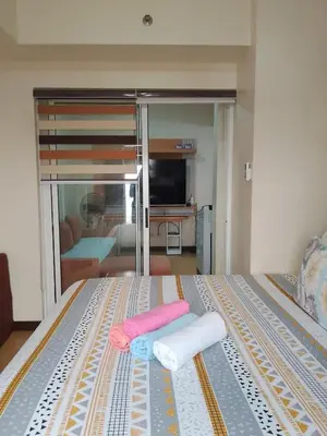 a bedroom with a bed with two towels and a television at Torre de Manila Taft Avenue near Luneta Park US Embassy Intramuros Ermita Manila in Manila