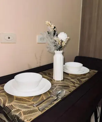 a table with two plates and a vase with flowers at Smdc Breeze Residences-The Metro Breeze-Staycation in Manila