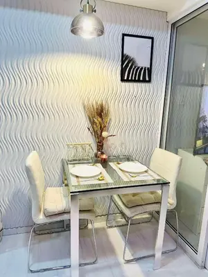 a dining table and chairs in a room with a wall at Condotels RQ Hob in Manila