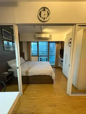 a bedroom with a bed and a clock on the wall at Staycation at Brgy Sucat in Manila