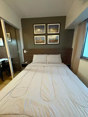 a large white bed in a bedroom with three pictures on the wall at Staycation at Brgy Sucat in Manila
