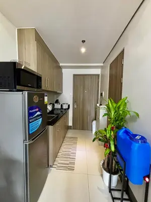 a kitchen with a stainless steel refrigerator and wooden cabinets at Fame Residence Tower 4 near Greenfield and Shaw MRT in Sampong