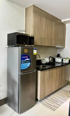 a kitchen with a stainless steel refrigerator and wooden cabinets at Fame Residence Tower 4 near Greenfield and Shaw MRT in Sampong