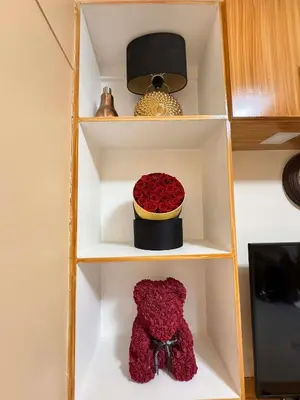 a shelf with a teddy bear and a bowl of roses at Kitty Breeze Staycation in Manila