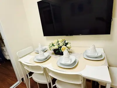 a white table with white dishes and a tv on a wall at The Camden Place Aesthetic Elegant Condo Unit 15 in Manila