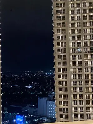 a view of a tall building at night at La Mari Staycation 2bedroom at Prisma Residences in Manila