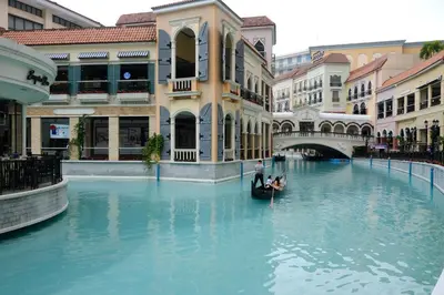 a man in a gondola in a canal in a city at Cozy Apartment in Venice Luxury Residences BGC in Manila