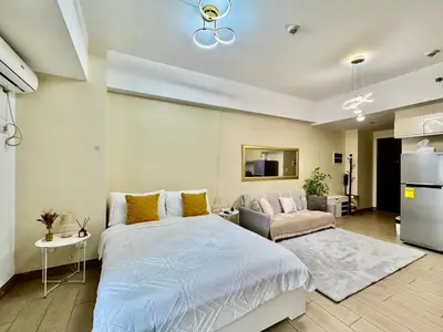 a bedroom with a large bed and a couch at Cozy Apartment in Venice Luxury Residences BGC in Manila