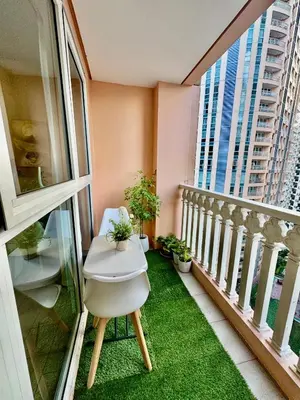 a balcony with a white chair and green grass at Cozy Apartment in Venice Luxury Residences BGC in Manila