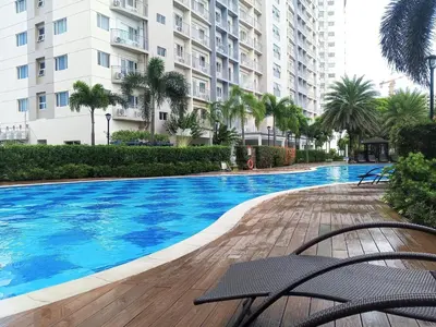 a swimming pool in front of a large building at Terra Nueve Escape - 1br with Balcony Staycation in Manila