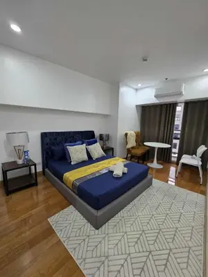 a bedroom with a blue bed and a living room at New 2BR Suite Milano Residences Poblacion Makati 110sqm in Sampong