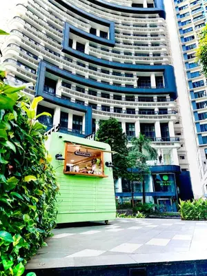 a small green building in front of a tall building at New 2BR Suite Milano Residences Poblacion Makati 110sqm in Sampong
