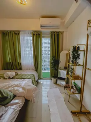 a bedroom with two beds and a window with green curtains at Staycation near Mall of Asia in Manila