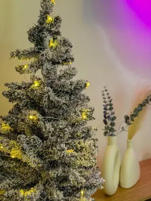 a christmas tree with lights next to two white vases at Staycation near Mall of Asia in Manila