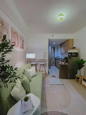 a living room with a green couch and a kitchen at Staycation near Mall of Asia in Manila