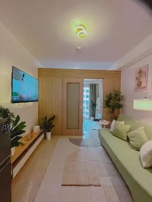 a living room with a green couch and a flat screen tv at Staycation near Mall of Asia in Manila