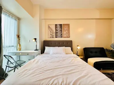 a bedroom with a large bed and a chair at 81 Newport Urban Chic Studio near NAIA Terminal 3 in Manila