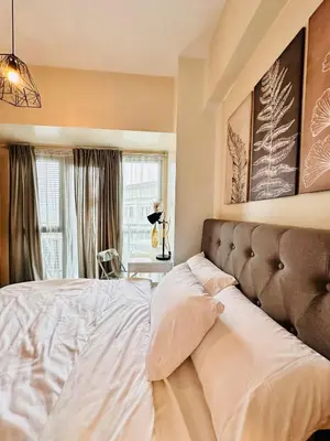 a bedroom with a large bed with white sheets at 81 Newport Urban Chic Studio near NAIA Terminal 3 in Manila