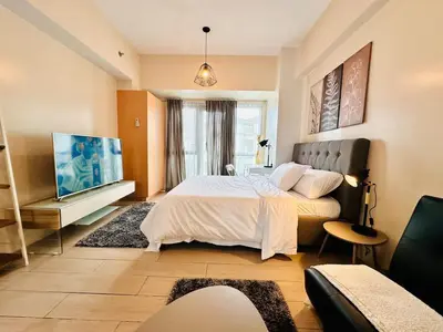 a bedroom with a large bed and a flat screen tv at 81 Newport Urban Chic Studio near NAIA Terminal 3 in Manila