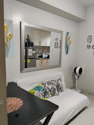 a bedroom with a mirror above a bed with a table at Sea Residences Anna Staycation in Manila