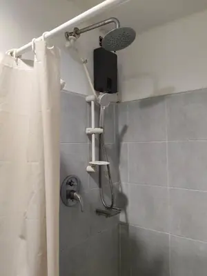 a shower with a shower curtain and a shower head at Sea Residences Anna Staycation in Manila