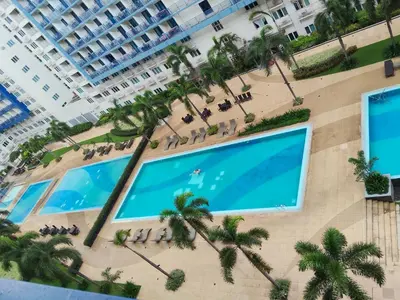 an overhead view of a large swimming pool in a building with palm trees at Sea Residences Anna Staycation in Manila