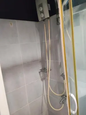 a shower with a hose attached to a wall at Sea Residences Anna Staycation in Manila
