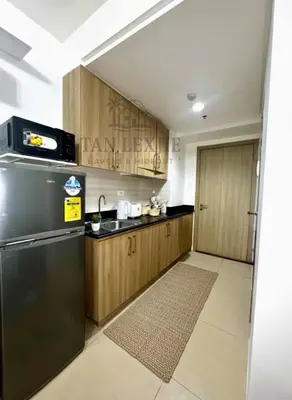 a kitchen with a black refrigerator and wooden cabinets at Tan LexJie Havens and Hideout in Manila