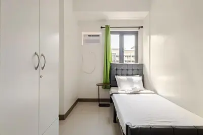 a small room with a bed and a window at Near SM BF & Shopwise SLEX Accessible 2BR for 4 in Manila